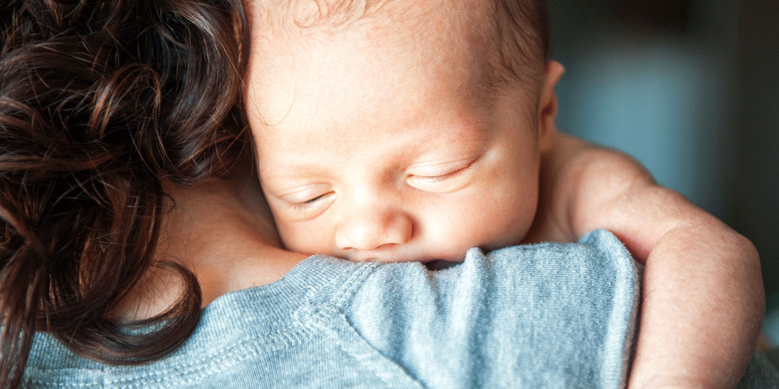 Baby hænger på mors skulder
