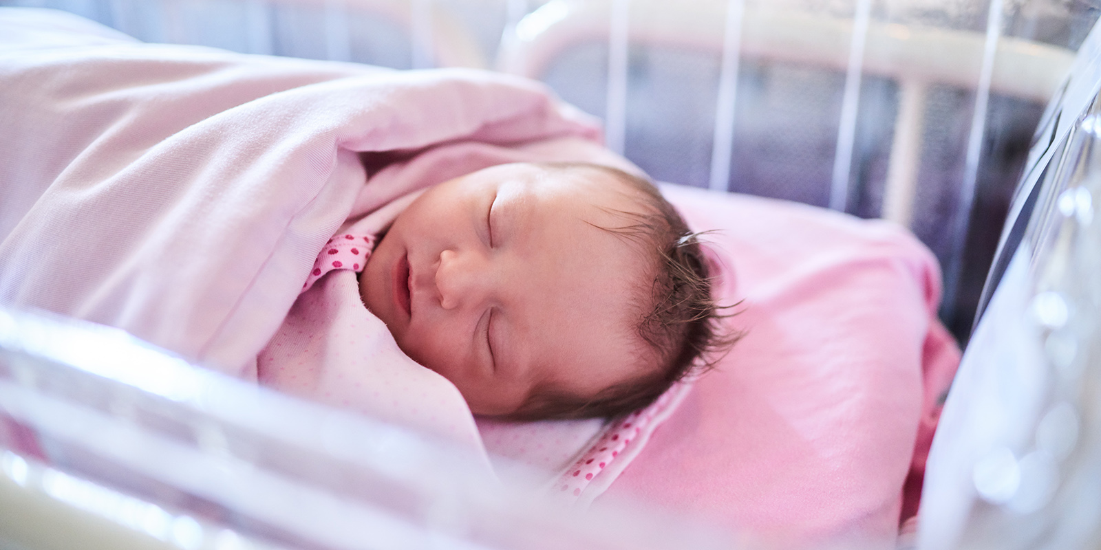 Nyfødt baby som ligger og sover i vugge